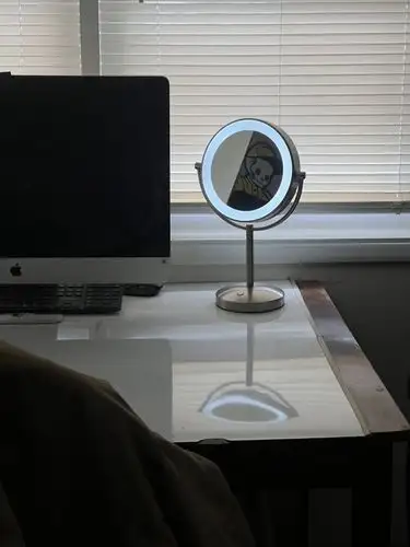 A glowing mirror reflects a screen, illuminating the workspace.